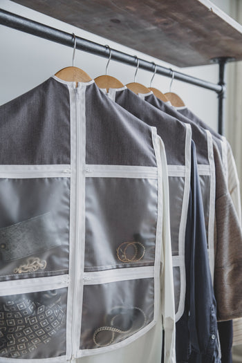 Five daily outfit organizers on a clothes rack with accessories and jewelry shown in pockets